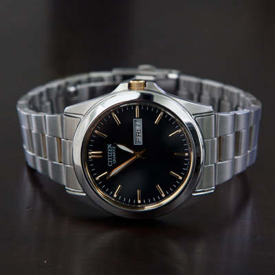 CITIZEN® Quartz Black Dial Men’s Watch - Handsome watch features precise Japanese quartz movement, day and date display and luminous gold tone hands with stainless steel case and band with push button release clasp.